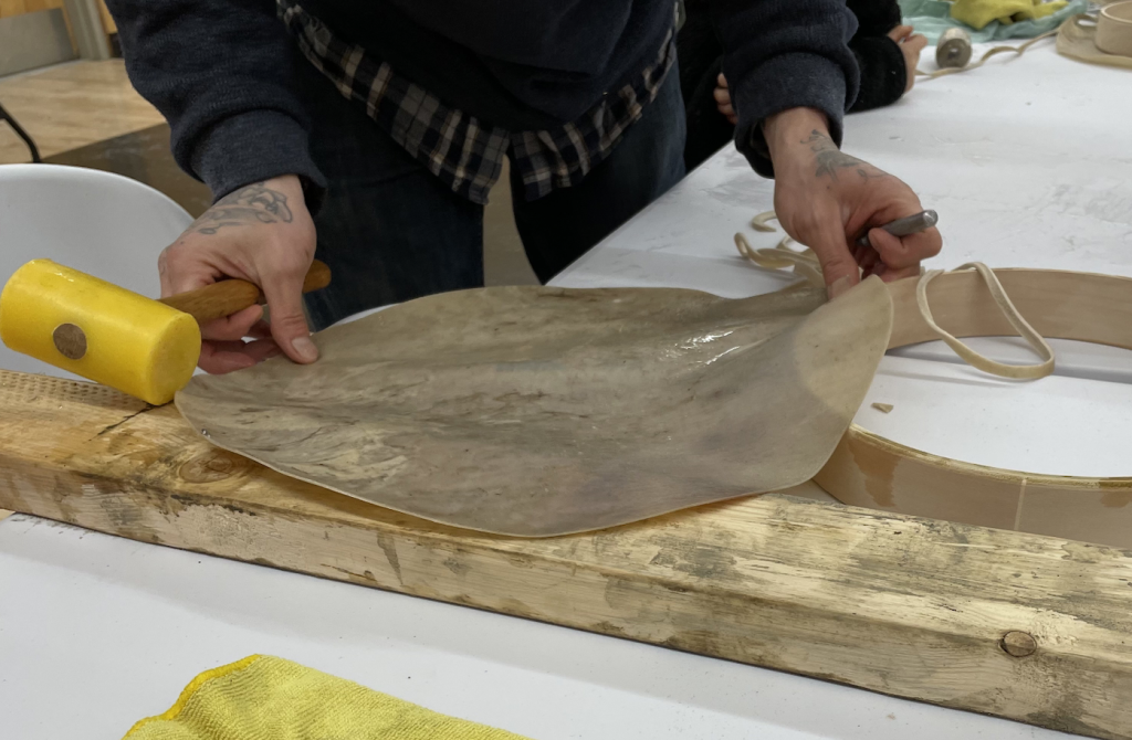 Image of a person's hands preparing hide for making a drum as part of a cultural documentary project.