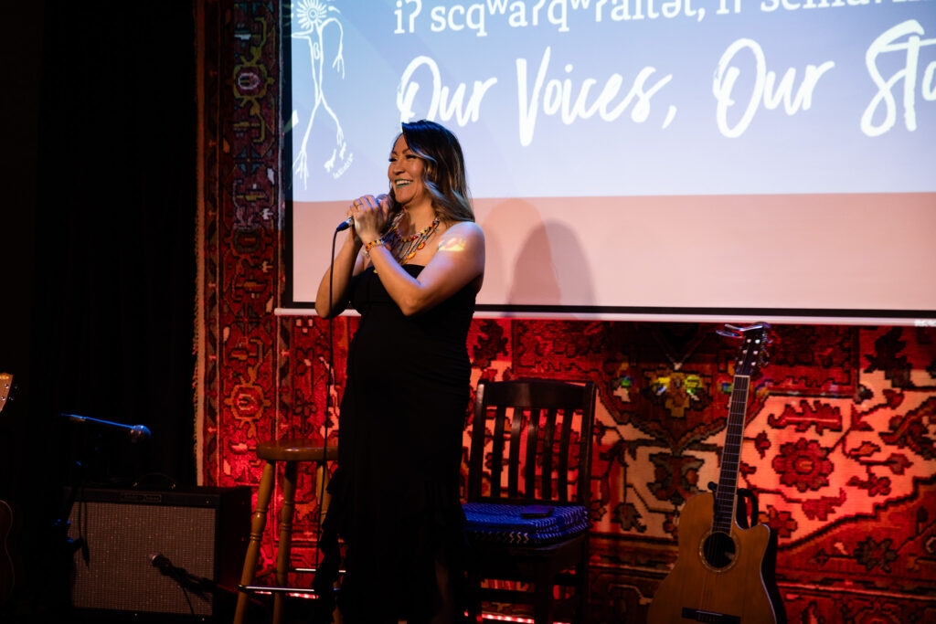 A person holds a microphone on a stage in a cafe