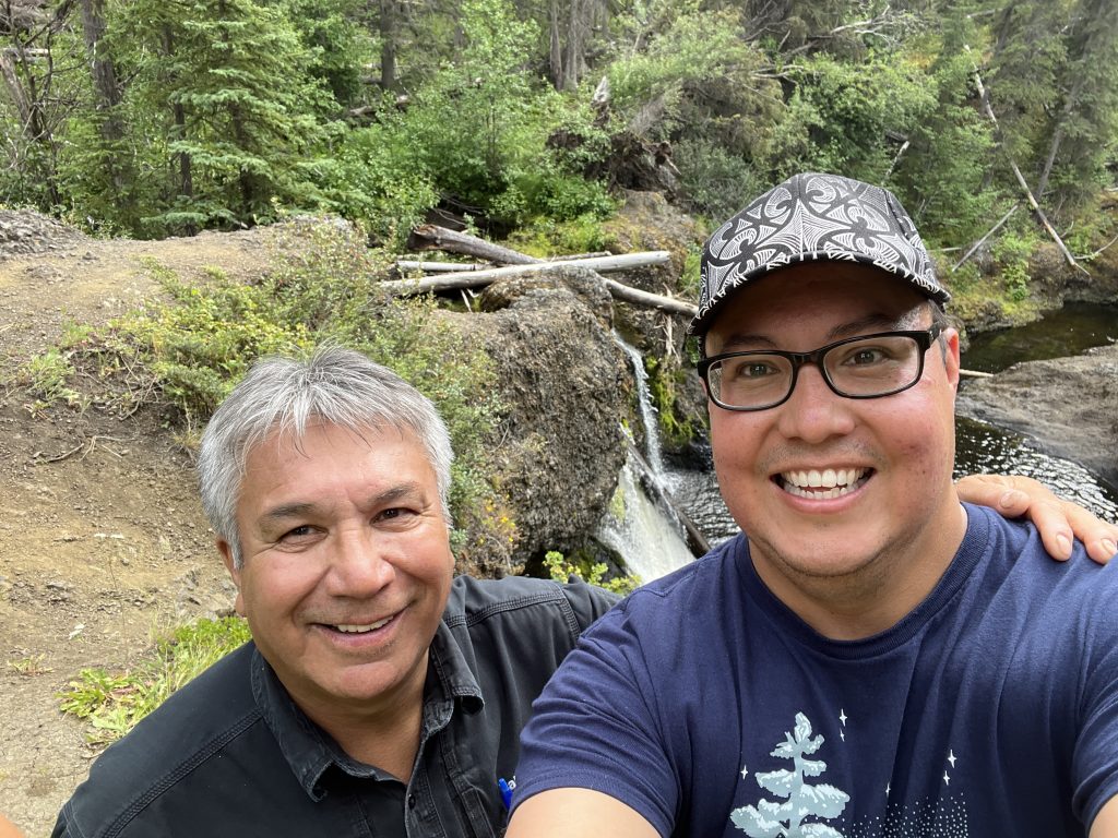 Two people beside a river in the woods.
