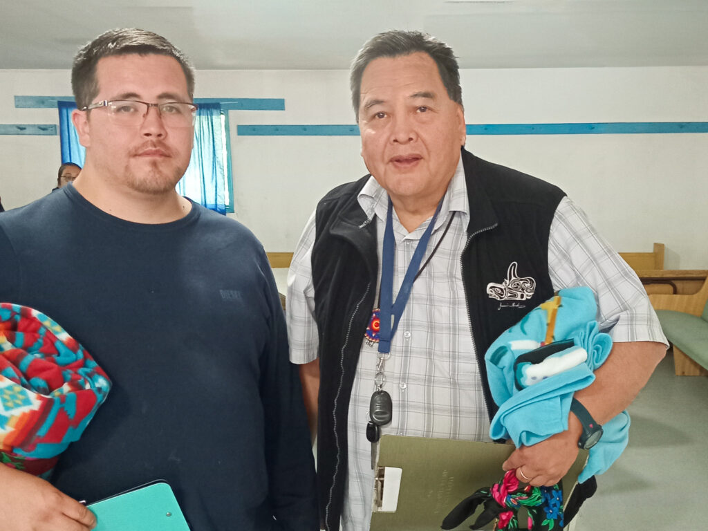 two people stand side by side holding clipboards and blankets