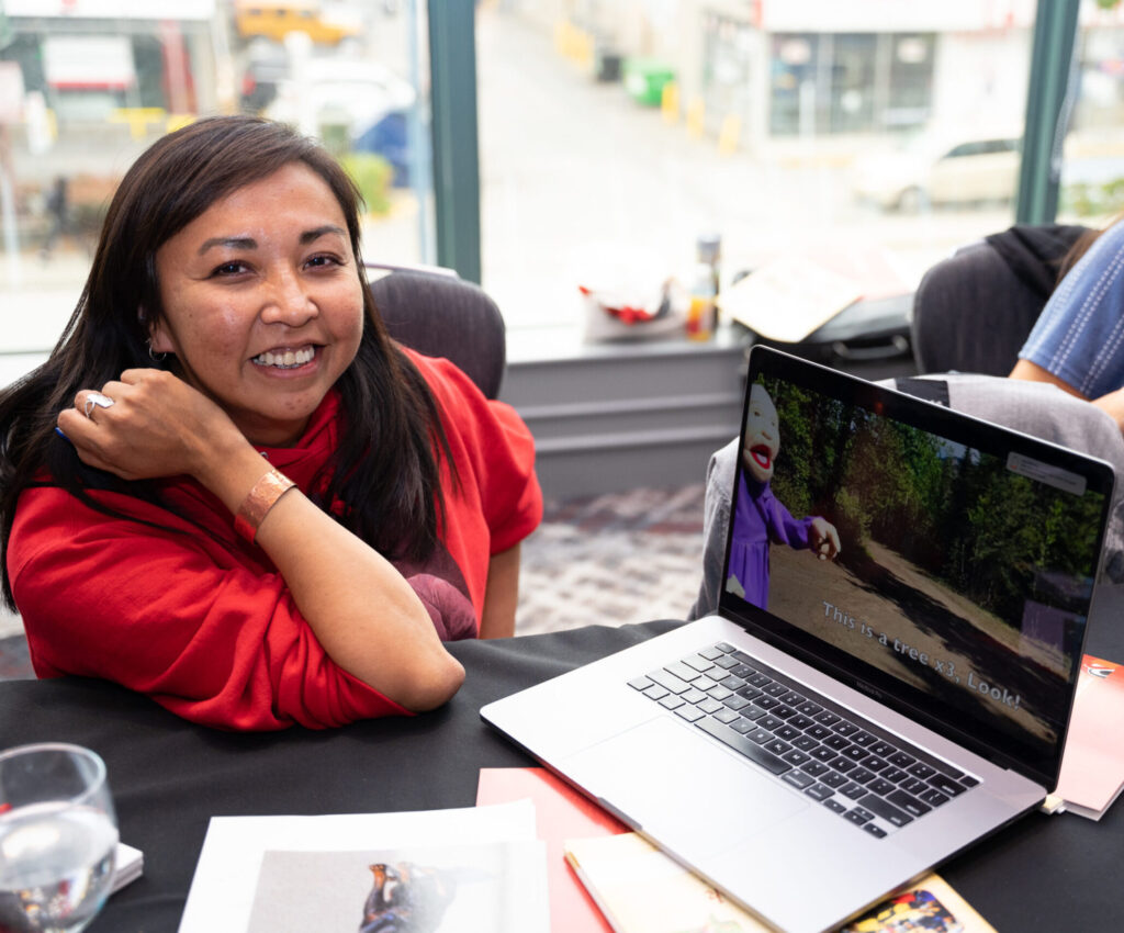 A smiling person shows a puppet video on a laptop