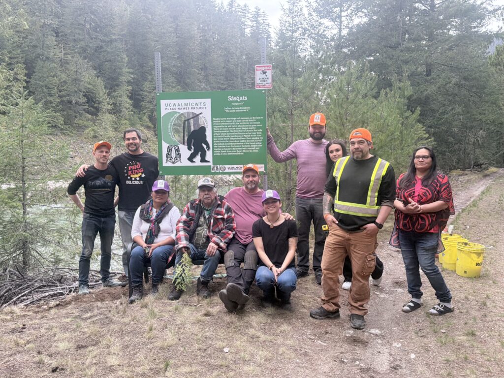 A group of smiling people stand around a recently installed place name sign.